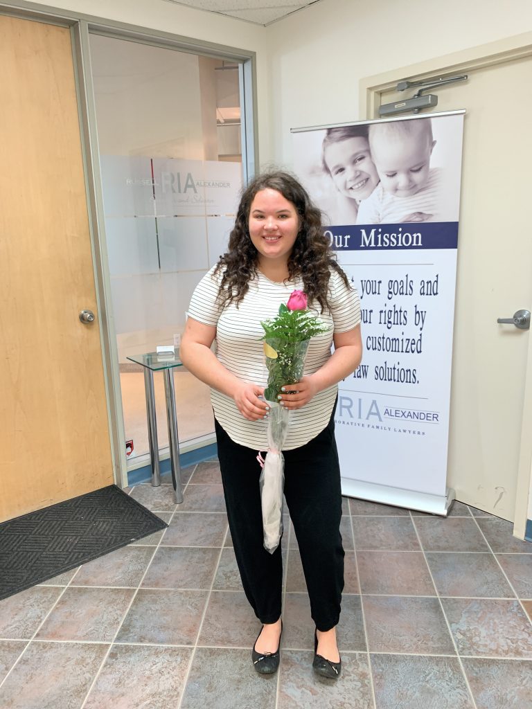 young lady holding a pink rose in front of law office