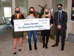 female student holding a cheque accompanied by 2 female and 1 male employee
